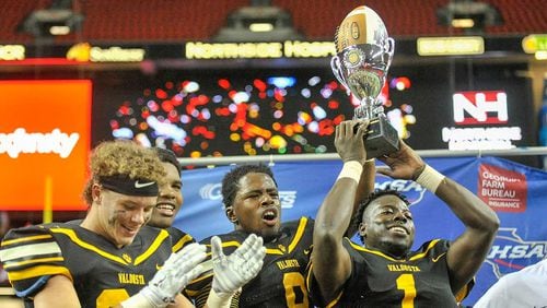 Valdosta seniors Wesley Veal (24, L-R), Devonnsha Maxwell (92), Jontae Baker (8), and Antwon Kincade hold their trophy high after beating Tucker 17-7 in the Class AAAAAA state title game at the Georgia Dome Friday.