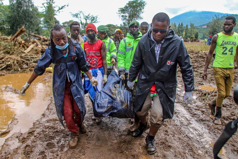 FILE - Kenya Red Cross workers and volunteers carry a man's body after floodwater washed away houses, in Kamuchiri Village Mai Mahiu, Nakuru County, Kenya, April 30, 2024. In a world growing increasingly accustomed to wild weather swings, the last few days and weeks have seemingly taken those environmental extremes to a new level. (AP Photo/Patrick Ngugi, File)