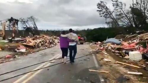 People walk amid debris in Lee County, Ala., after what appeared to be a tornado struck in the area March 3. At least 23 people were killed in Alabama from storms that rumbled through Georgia, Alabama and Florida last weekend.