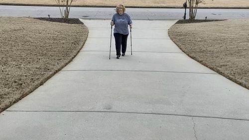 Stephanie Schroeder of McDonough taking a walk up her driveway. Because long COVID has wreaked havoc with her balance, she says she uses the walking sticks to steady herself. “Some days, I’m all right, but I can’t tell you which days I will feel good,” she said. “It’s all very frustrating because you know what you were capable of doing before.” (Contributed)