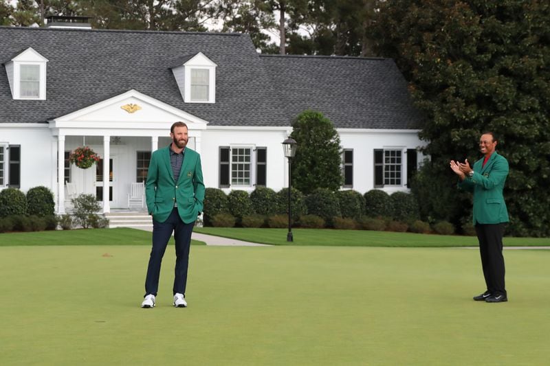Last year's Masters champion Tiger Woods (right) applauds after presenting Dustin Johnson his first green jacket in front of Butler Cabin for winning the Masters Tournament Sunday, Nov. 15, 2020, at Augusta National. (Curtis Compton / Curtis.Compton@ajc.com)