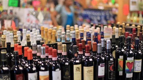 A customer walks by shelves full of red wine at Beverage City in Fairburn. JASON GETZ FOR THE AJC