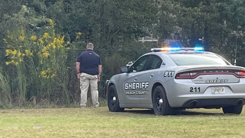 A Peach County deputy stands near the scene of a shooting that killed a 22-year-old man Wednesday.