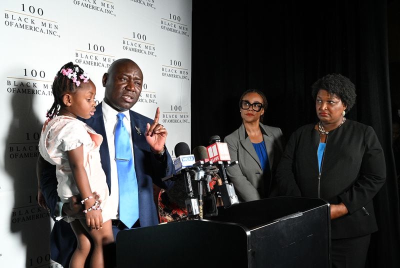 Civil rights attorney Ben Crump, holding 3-year-old Maria Grier, speaks as Georgia gubernatorial candidate Stacey Abrams (right) looks on.