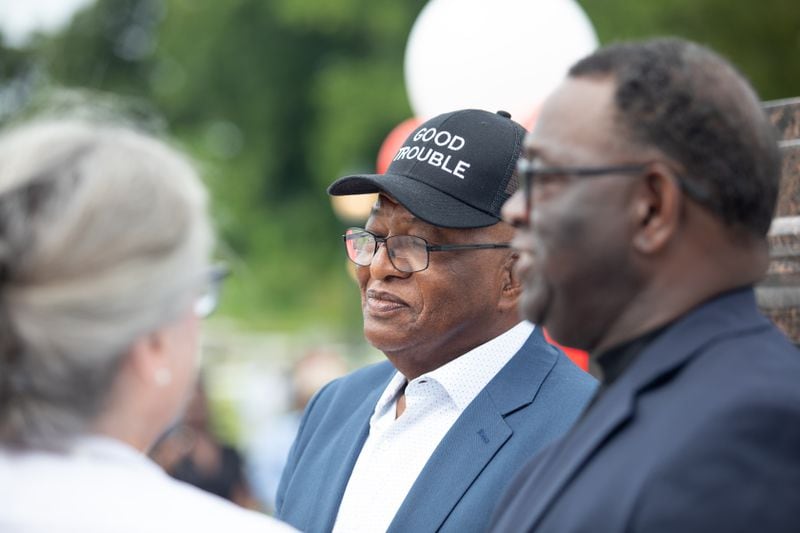 Samuel Lewis, wearing a "Good Trouble" hat and Henry Lewis, the two younger brothers of the late Congressman John Lewis, in front of his statue at Rodney Cook Sr. Park in Vine City in Atlanta, GA., on Wednesday, June 7, 2021. (Photo/ Jenn Finch for the Atlanta Journal-Constitution)