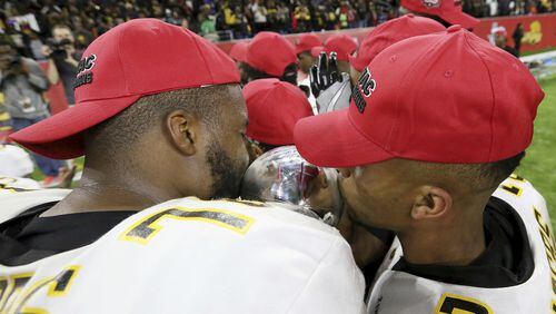 Grambling State’s Trent Scott, left, and Tyler Oliver kiss the Southwestern Athletic Conference championship trophy after defeating Alcorn State in the NCAA college football game Saturday, Dec. 3, 2016, in Houston. (Yi-Chin Lee/Houston Chronicle via AP)