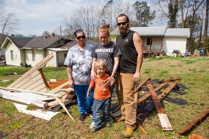 (Left to right) Melissa Allen, Charles Bergeron, Vincent Bergeron and Emily Bergeron pose in their backyard by the roof of their house, on Friday, March 26, 2021, in Cedartown, Georgia. The storm ripped the roof off of the Bergeron household and caused severe damage in several areas throughout the town. No casualties were reported.  CHRISTINA MATACOTTA FOR THE ATLANTA JOURNAL-CONSTITUTION.