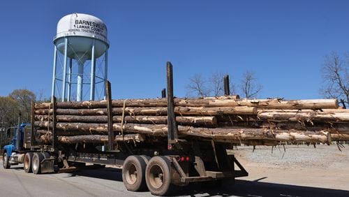 A log truck drives by the Barnesville water tower earlier this month. The state Senate Transportation Committee voted Monday in favor of legislation that would allow trucks hauling forestry and agricultural products to carry heavier loads until July 1, 2024. (Natrice Miller/ Natrice.miller@ajc.com)