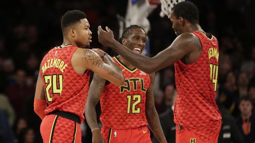 Atlanta Hawks' Kent Bazemore, left, celebrates his three-point basket with Taurean Prince, center, and Dewayne Dedmon during the last seconds of the second half of an NBA basketball game against the New York Knicks, Sunday, Feb. 4, 2018, in New York. (AP Photo/Seth Wenig)
