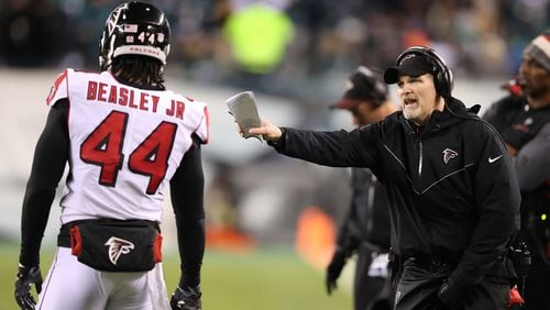 Falcons head coach Dan Quinn confers with Vic Beasley Jr. between defensive plays against the Eagles in their NFC Divisional Game on Saturday, Jan. 13, 2018, in Philadelphia. \
