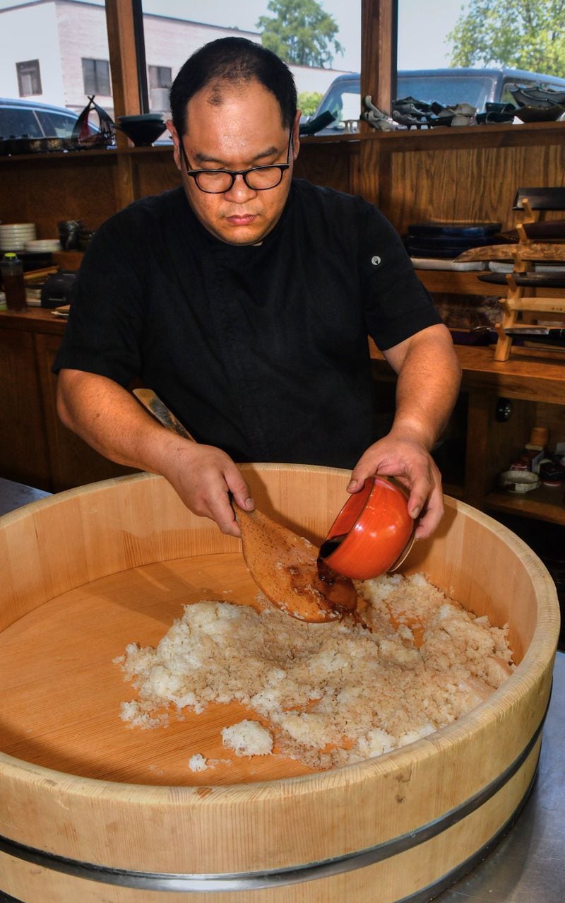 Chef Yu seasons rice with red vinegar in a large hangiri bowl. (CHRIS HUNT FOR THE ATLANTA JOURNAL-CONSTITUTION)