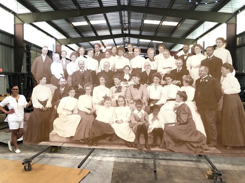 Atlanta Historian Karcheik Sims-Alvarado (standing lower left) stands behind the massive 17x8 reproduction of the turn of the 20th century photograph of the Atlanta University faculty. The photo includes, W.E.B. Du Bois (last man on the top row to the right); Alonzo Herndon (top row on the left); Atlanta University President Horace Bumstead (middle row with beard wearing a chain on his vest)