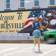 A pedestrian crosses North Harris Street in downtown Sandersville, where a mural is dedicated to Olympic gold medalist and Atlanta Dream player Allisha Gray on Tuesday, April 14, 2024. (Miguel Martinez / AJC)