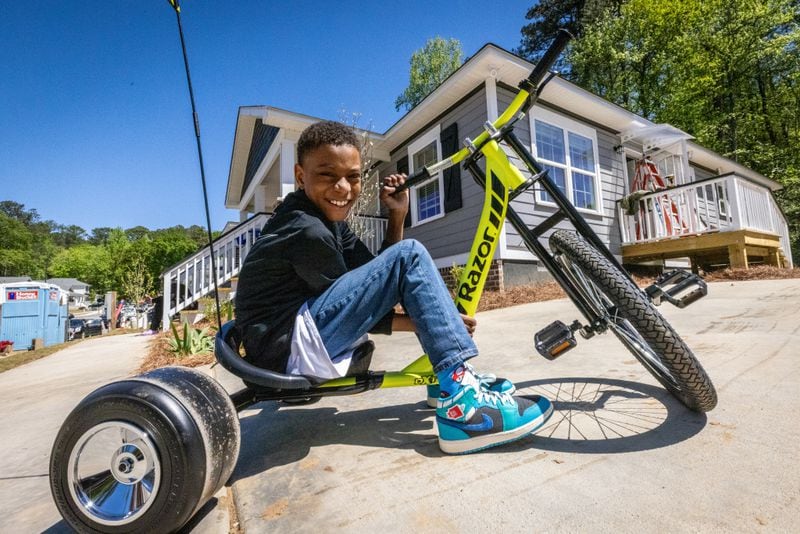 Kingston Jackson, 11, poses for a photograph in front of his family's new Clark Howard-sponsored Atlanta Habitat for Humanity home #99 in Atlanta on Saturday, April 13, 2024. Jackson's family will move into their new home in about five to six weeks. (Steve Schaefer/ steve.schaefer@ajc.com)
