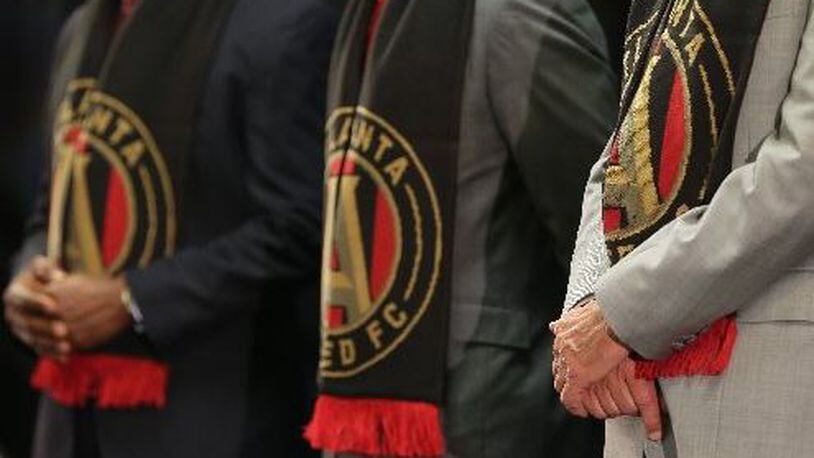 August 4, 2015 Decatur: Decide DeKalb President Ray Gilley, from left, DeKalb Interim CEO Lee May and Atlanta United FC owner Arthur Blank sport their team scarves during an August 4 announcement that Atlanta United FC would locate their headquarters and practice facility in DeKalb Couny. (Ben Gray / bgray@ajc.com)