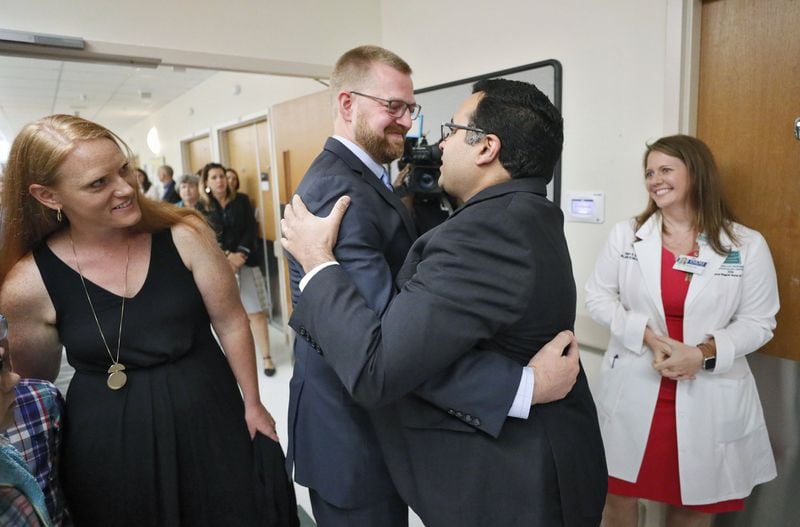 Dr. Kent Brantly is greeted by Dr. Aneesh Mehta, one of the doctors that treated him, as he enters the Serious Communicable Diseases Unit for a tour. At left is his wife, Amber and at right is Sharon Vanairsdale, a member of the nursing staff that assisted with his care. Bob Andres / robert.andres@ajc.com