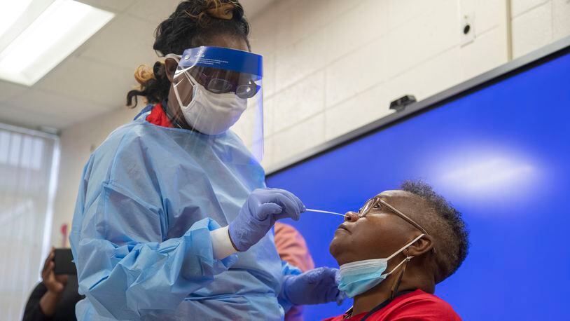 Clayton County Public Schools healthcare tech Glissa Nash takes a COVID-19 testing swab from G.P. Babb Middle School teacher Ruth Caine during a vaccination and testing drive in Forest Park Tuesday, Sept. 21.  (Alyssa Pointer/The Atlanta-Journal Constitution)