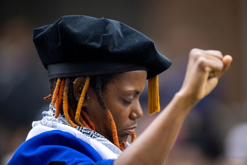 Assistant Professor Taura Taylor raises her fist in protest of the Gaza war at the Morehouse commencement ceremony in Atlanta on Sunday, May 19, 2024. (Arvin Temkar / AJC)