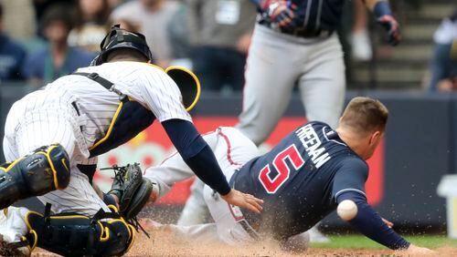 Braves first baseman Freddie Freeman beats the tag of Brewers catcher Manny Pina on an RBI double by second baseman Ozzie Albies, giving the Braves a 2-0 lead in the third inning of NLDS Game 2 on Saturday. Curtis Compton / Curtis.Compton@ajc.com