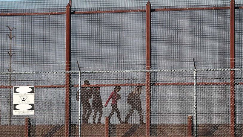 Migrants walk together along the U.S./Mexican border wall as they look to turn themselves over to the U.S. Border Patrol as they seek asylum in the United States on June 04, 2019 in El Paso, Texas. (Photo by Joe Raedle/Getty Images)