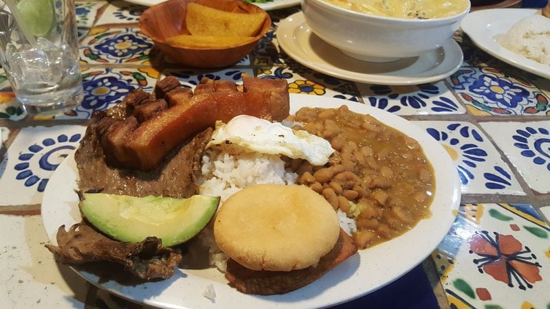 The Bandeja Paisa is a traditional, meat-centric platter from the Paisa region in the northwest of Colombia. This platter is usually piled with grilled steak, pork skins, fried plantain, rice, beans and avocado, Some Atlanta restaurants offer a mini version, such as that from La Casona in Doraville (pictured). LIGAYA FIGUERAS / LFIGUERAS@AJC.COM