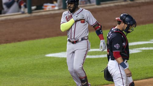 The Braves' Marcell Ozuna nears home after hitting a home run, next to Washington Nationals catcher Yan Gomes during the eighth inning of a  game in Washington on Friday. (AP photo)