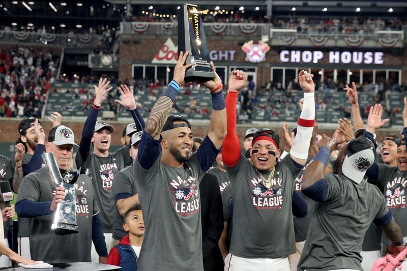 Braves left fielder Eddie Rosario hoists the Most Valuable Player trophy after the Braves' 4-2 win over the Los Angeles Dodgers in Game 6 at the NLCS Saturday, Oct. 23, 2021, at Truist Park in Atlanta. (Hyosub Shin / Hyosub.Shin@ajc.com)