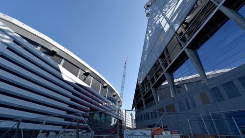 The new Falcons stadium overshadows the Georgia Dome as construction continues. Construction crews celebrated the near completion of the the fixed roof at Mercedes Benz Stadium Wednesday October 19, 2016 by signing a beam and then lifting it into place. The completed stadium will use more than 27,000 tons of steel. Installation of the retractable roof will begin next. BRANT SANDERLIN/BSANDERLIN@AJC.COM