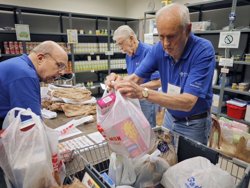 Volunteers John Lounsbury (from left), Ed Osowski and Lloyd Foster fill food orders at Norcross Cooperative Ministry, one of the busiest co-ops in Gwinnett County, on July 13, 2018. BOB ANDRES /BANDRES@AJC.COM