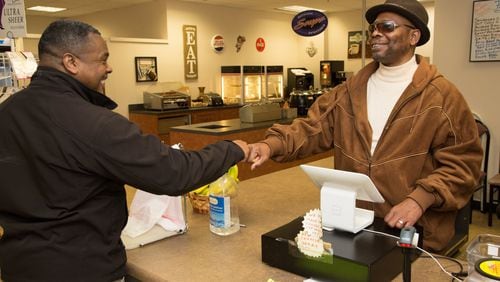 Anthony Brewer (left) fist pumps Eddie Mial, who runs a snack shop in the basement of the DeKalb County Courthouse in Decatur. The gregarious Mial greets every customer who comes in the store. (Photo by Phil Skinner)