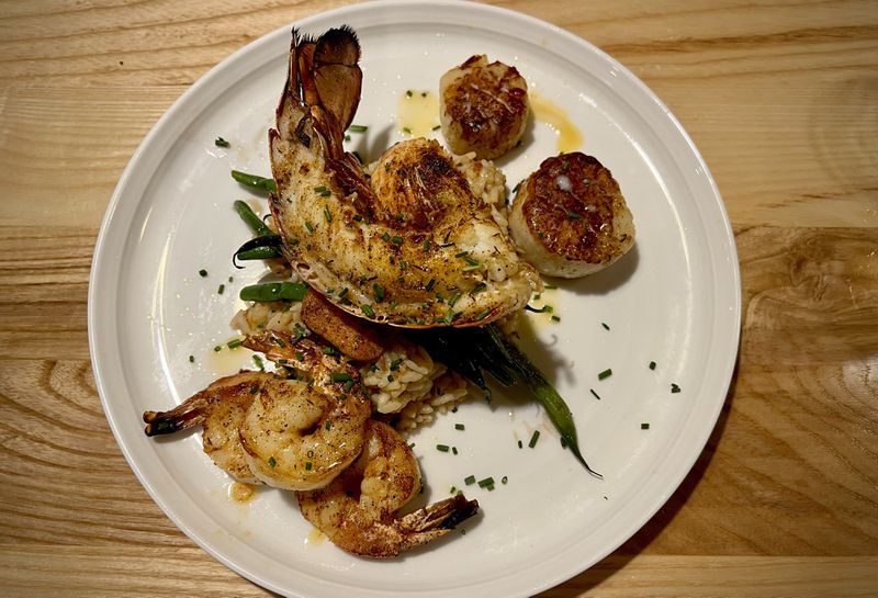 This broiled seafood platter at Mac's featured lobster, scallops and halibut over dirty rice and green beans. Henri Hollis/henri.hollis@ajc.com