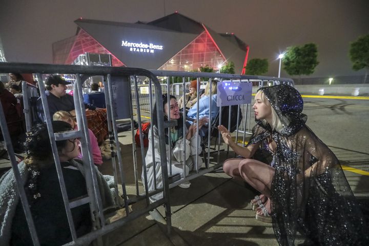 Cami Obanion (left) and Ashley Dawson (right) who came dressed in Taylor Swift attire talk Together as Taylor Swift fans braved cooler morning temperatures and drizzle while they waited in line before daybreak at the Georgia World Congress Center International Plaza outside Mercedes-Benz Stadium to buy official Swift merchandise on Thursday, April 27, 2023.  (John Spink / John.Spink@ajc.com)