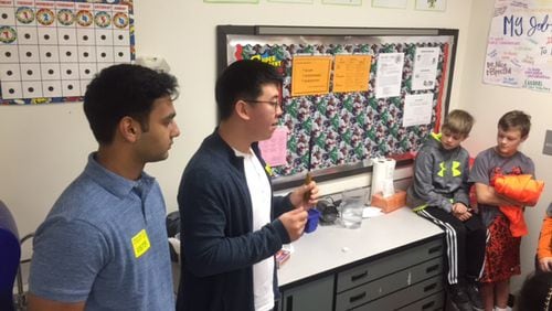 Alpharetta High School students teach a science lesson to Creek View students Matthew Kloecker and Wesley Austin, from Adrienne Hunter’s fourth-grade class.