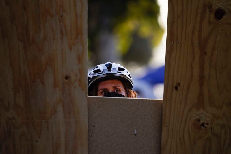 A demonstrator shields themselves behind a barricade at an encampment on the UCLA campus, after nighttime clashes between Pro-Israel and Pro-Palestinian groups, Wednesday, May 1, 2024, in Los Angeles. (AP Photo/Ryan Sun)