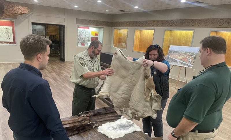 Valarie Ikhwan, second from right, recently showed colleagues some animal pelts intended for a new hands-on display at the Etowah Indian Mounds learning center. The pelts representing protected species are fake. Ikhwan is working closely with the Muscogee (Creek) Nation to ensure historical accuracy and sensitivity as part of the $90,000 overhaul of the historic site’s museum. “We want to be culturally sensitive. When the archaeology was done in the 1950s and 1960s, it was done without any permission of tribal affiliates,” said Ikhwan, the Georgia Natural Resources Department’s chief interpreter. “So we are trying to heal some of those wounds.” Jeremy Redmon/jredmon@ajc.com