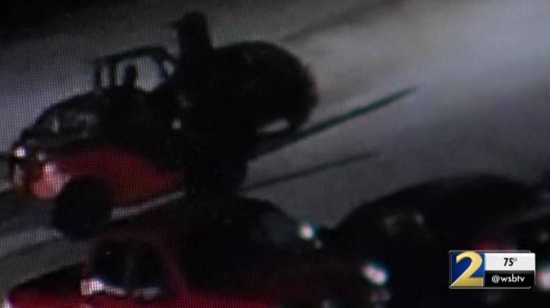 This is a screenshot of surveillance video that shows a man driving a forklift towards a fence to break through it.