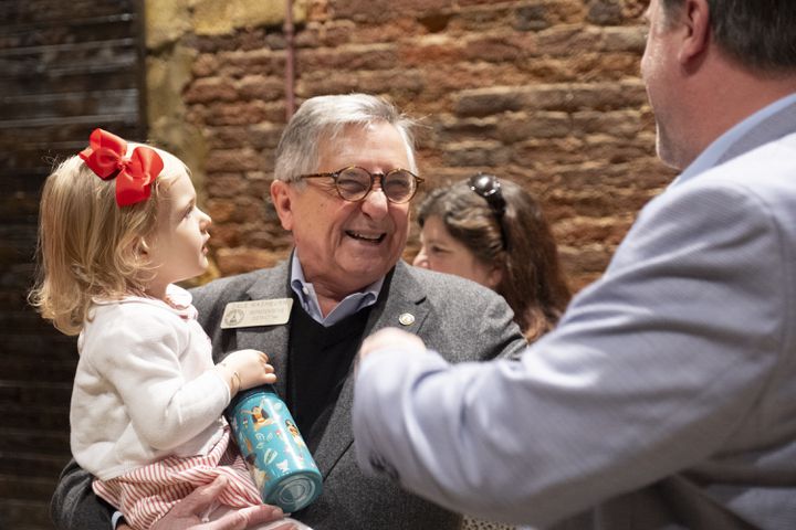Rep. Dale Washburn (R-Macon) holds his youngest granddaughter, Rosalie Anne, 2, as he socializes at the Wild Hog Supper, which is the traditional kick off to the legislative session in Atlanta on Sunday, Jan. 7, 2024.   (Ben Gray / Ben@BenGray.com)