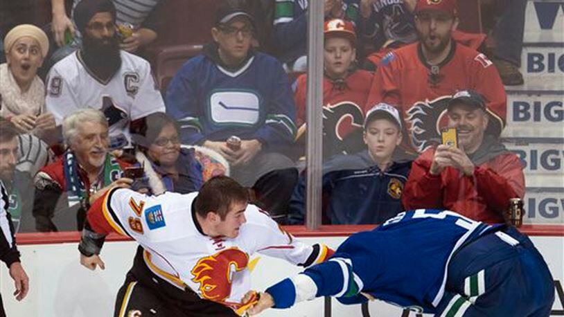Fans watch as Vancouver Canucks defenseman Luca Sbisa (5) and Calgary Flames left wing Micheal Ferland (79) fight during the first period of an NHL hockey game Saturday, Feb. 6, 2016, in Vancouver, British Columbia. (Jonathan Hayward/The Canadian Press via AP)