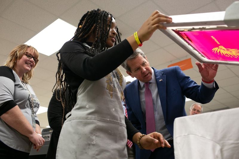 Gov. Brian Kemp watches a student print a T-shirt using a screen printing press during a tour of McEachern High School in Powder Springs on Thursday, Feb. 13, 2020. REBECCA WRIGHT / FOR THE AJC