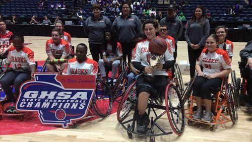 Senior Jordan Kozloski holds the trophy after scoring 19 points to lead the Houston County Sharks to a 39-17 victory over the Gwinnett Heat in the wheelchair basketball state championship game Friday at the Macon Coliseum.