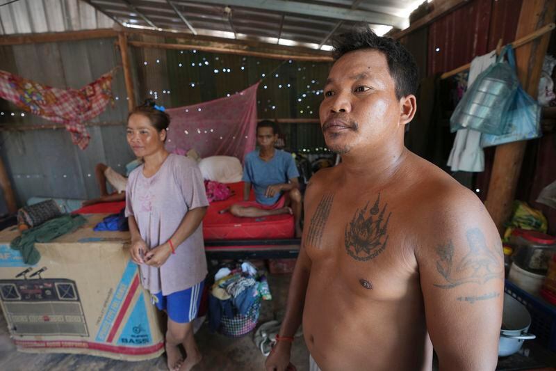 Yun Chantha, 40, right, and his wife Yem Srey Pin, 35, left, stand at their home in Run Ta Ek village in Siem Reap province, Cambodia on April 2, 2024. It's been more than a year since Yem Srey Pin moved with her family from the village where she was born on Cambodia's Angkor UNESCO World Heritage site to Run Ta Ek, a dusty new settlement about 25 kilometers (15 miles) away. Cambodia's program to relocate people living on the famous Angkor archaeological site is drawing international concern over possible human rights abuses, while authorities maintain they're doing nothing more than protecting the UNESCO World Heritage Site from illegal squatters. (AP Photo/Heng Sinith)