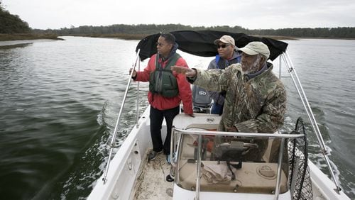 Local historian Hanif Haynes, foreground, along with Georgia state Sen. Lester Jackson, right, and local historian Jamal Touré, stops his boat near the mouth of Runaway Negro Creek near Pin Point in Savannah. Savannah-area residents want the official name of a creek on Skidaway Island to be changed from Runaway Negro Creek to Freedom Creek. (AJC Photo/Stephen B. Morton)