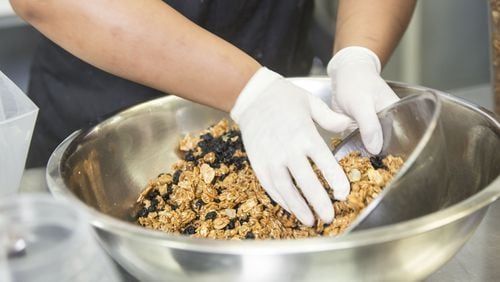 Nadia Campbell, an employee of Eugene Kitchen, mixes granola during her afternoon shift. The granola is provided in a diverse group of in-flight dishes for Delta. Chad Rhym/ Chad.Rhym@ajc.com File photo