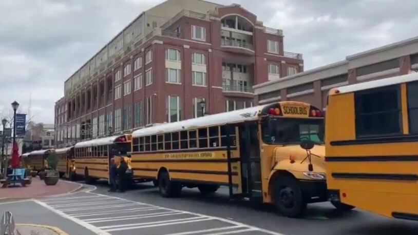 A group of 72 school buses featuring anti-sex trafficking messages created a mile-long moving billboard along Atlanta’s streets on Wednesday. AJC photo.