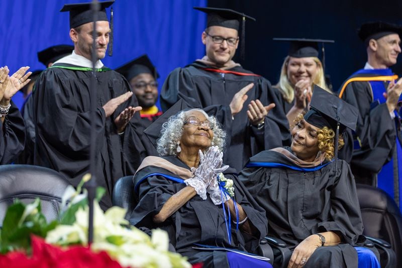Myra Payne Elliott, 90, reacts to applause while seated next to her daughter Jocelyn Gleaton at Georgia State University’s graduation ceremony in Atlanta on Wednesday, Dec. 14, 2022. GSU presented honorary degrees to Elliott and two other Black women, now deceased, who sued to integrate the school but never enrolled. (Arvin Temkar / arvin.temkar@ajc.com)