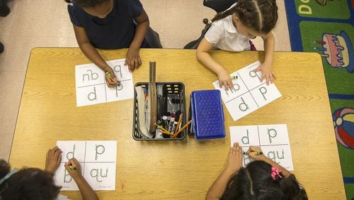 Kindergarten students trace letters and digraphs onto a plastic gridded sheet during their phonics lesson at Benteen Elementary School in Atlanta. The plastic grid is used as a sensory tool to help students remember their lesson. AJC FILE PHOTO.