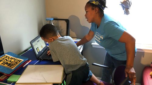 Tiffany Shelton helps her 7-year-old son, P.J. Shelton, a second-grader, during an online class at their home in Norristown, Pa., on Thursday, Sept. 3, 2020. Norristown Area School District plans to offer online-only instruction through at least January 2021. (AP Photo/Michael Rubinkam)