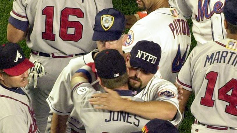 Mets' Rick White, wearing an NYPD cap, embraces Atlanta's Chipper Jones before the start of a game at Shea Stadium Friday, Sept. 21, 2001, in New York. This was the first baseball game in New York since the World Trade Center attack of Sept. 11. The Mets wore caps honoring the police and fire departments for the game.