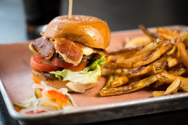 The Big Greasy brisket burger topped with white cheddar cheese curds, lettuce, tomatoes, and house-made bacon jam and garlic aioli on a toasted bun. Photo credit- Mia Yakel.