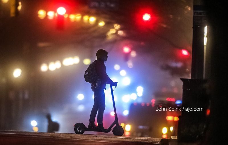 Becca Kiriazes scoots along 7th Street at Peachtree Street in the fog. Visibility dropped below a quarter-mile in Atlanta on Monday morning. JOHN SPINK / JSPINK@AJC.COM